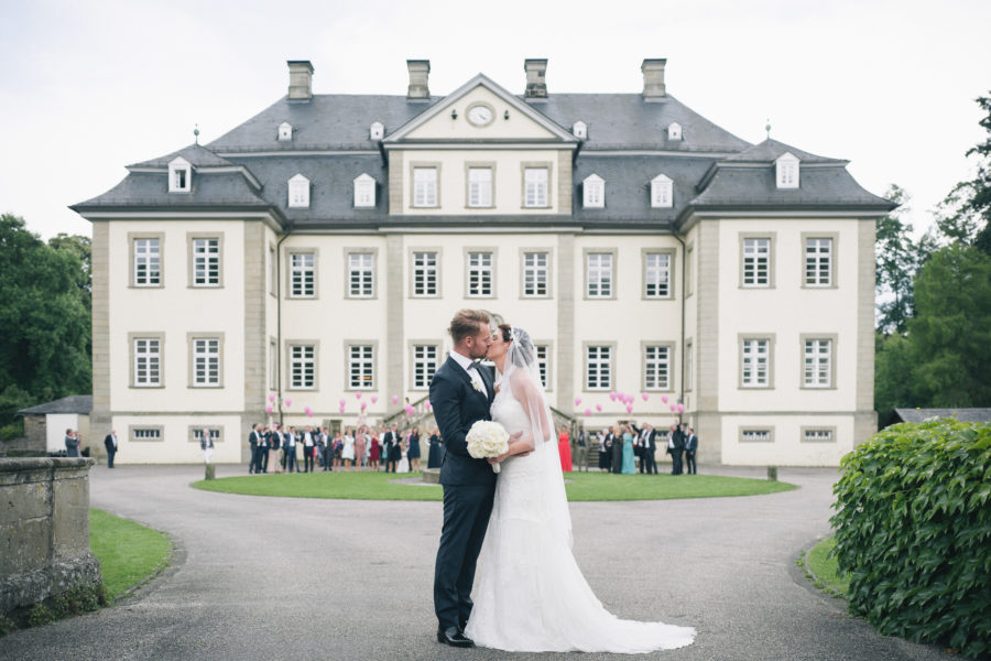 Brautpaar küsst sich vor dem Schloss Körtlinghausen