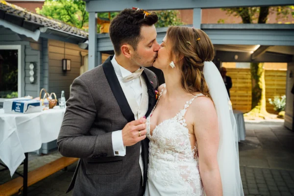 Ein Brautpaar küsst sich beim Sektempfang im Garten von Bökamp in Rietberg