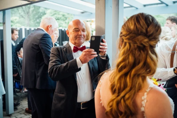 Ein Gast fotografiert dieBraut mit seinem Smartphone