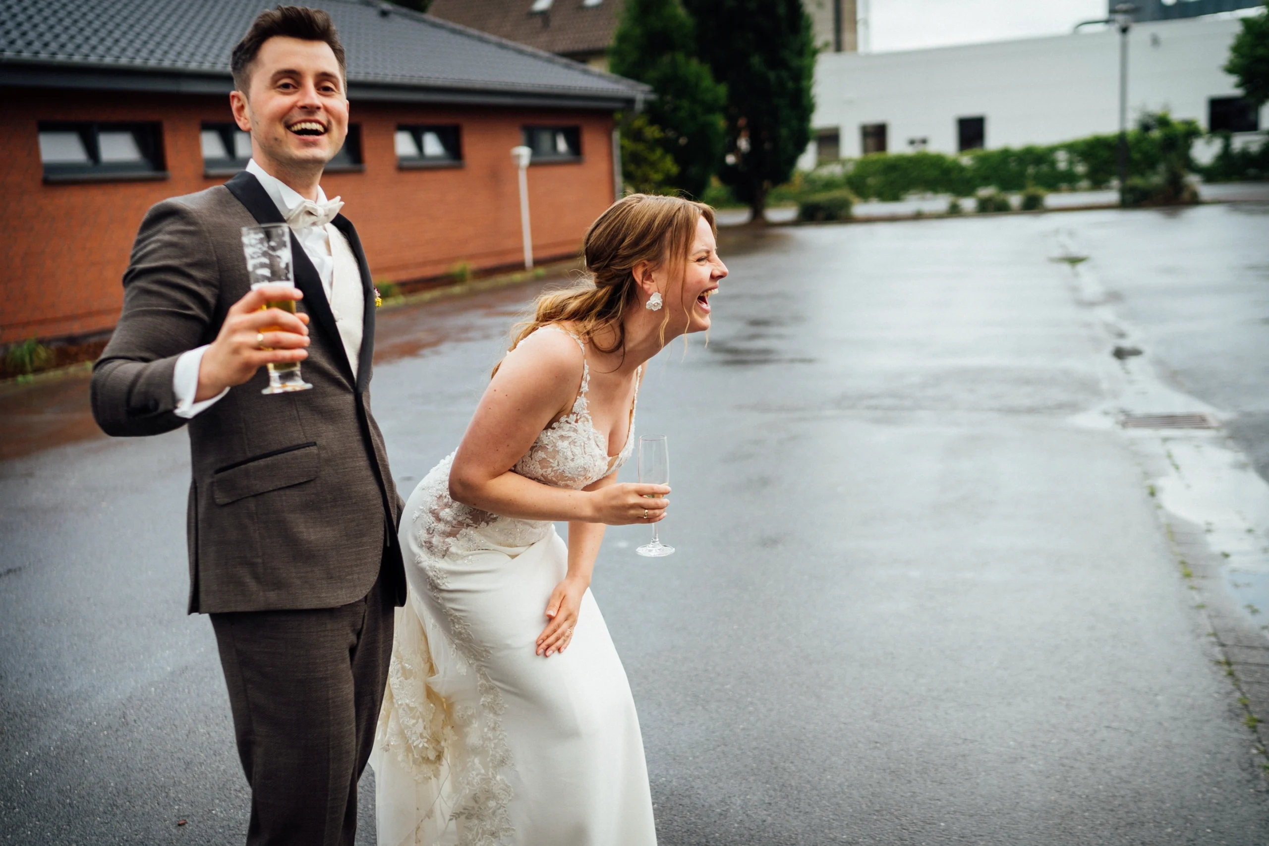 Sina & Bogdan - Eine freie Trauung in Rietberg Das Brautpaar lacht nach einem Regenschauer aus vollem Herzen auf dem Parkplatz von Bökamp in Rietberg