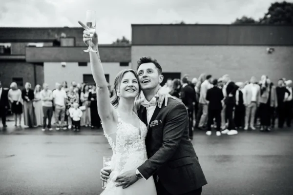 Das Brautpaar sieht den Luftballons nach. Im Hintergrund ist die Hochzeitsgesellschaft zu sehen