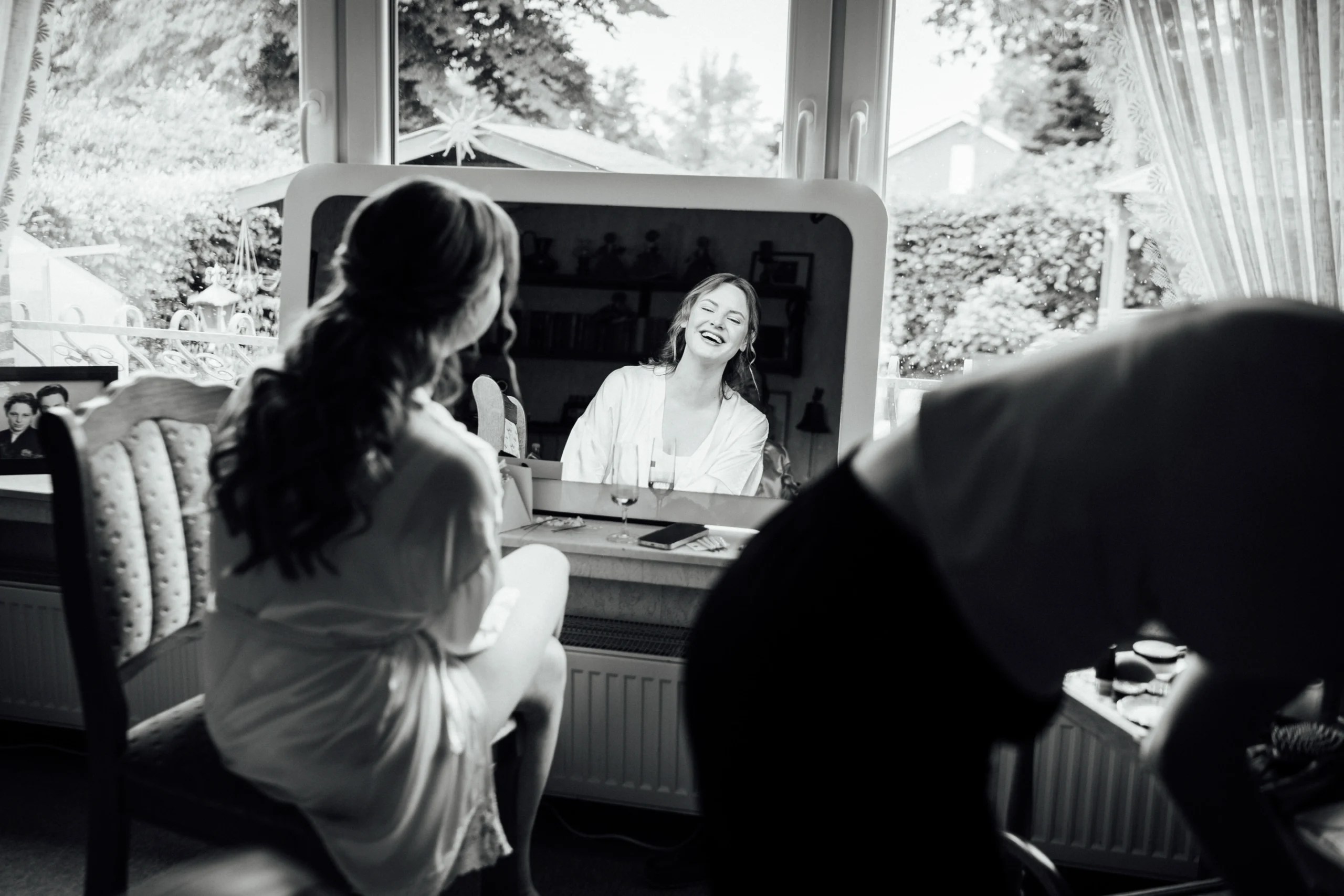 Sina & Bogdan - Eine freie Trauung in Rietberg Eine Braut sitzt beim Getting Ready lachend vor einem großen Spiegel