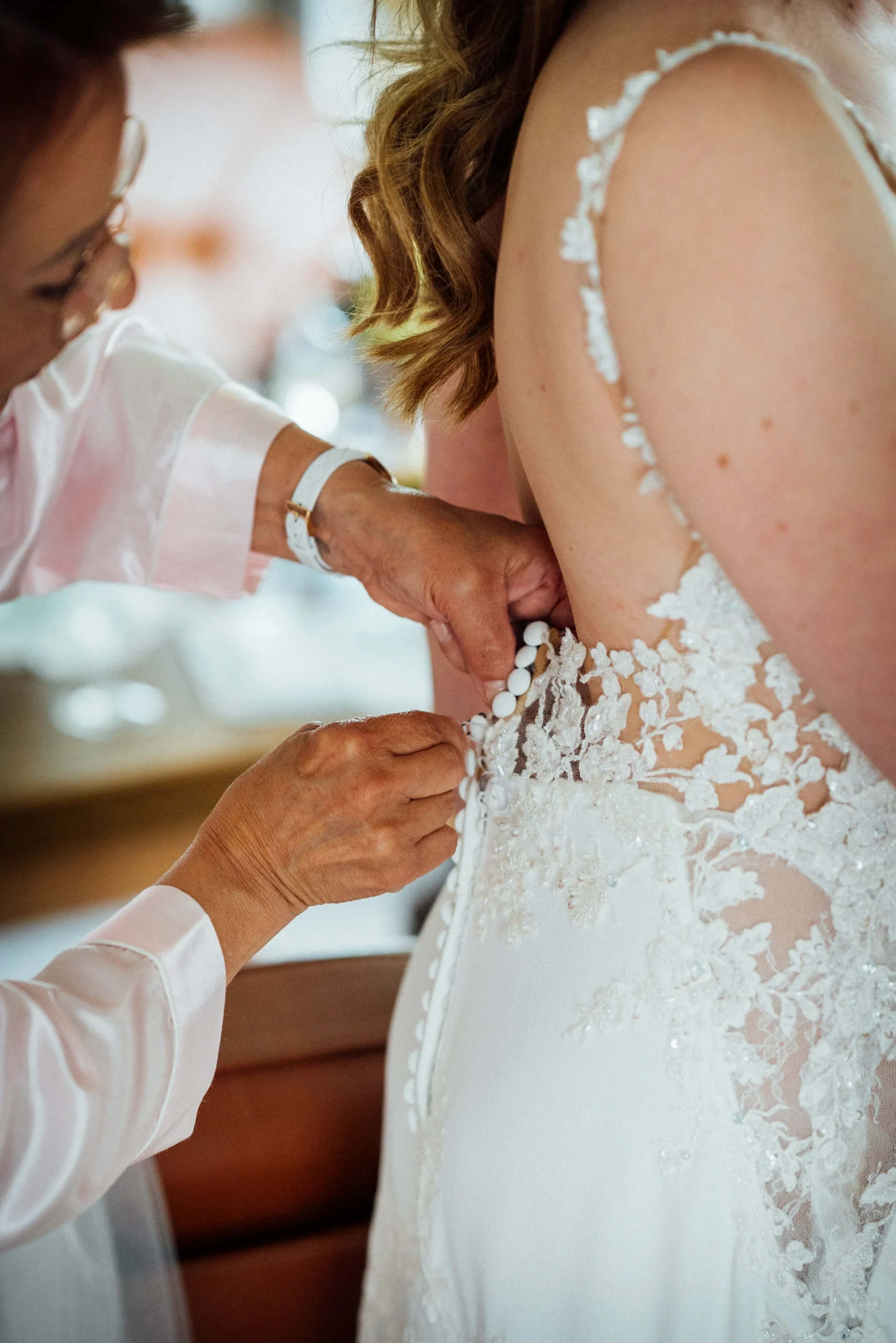 Die Mutter der Braut hilft der Braut beim Anziehen des Kleides
