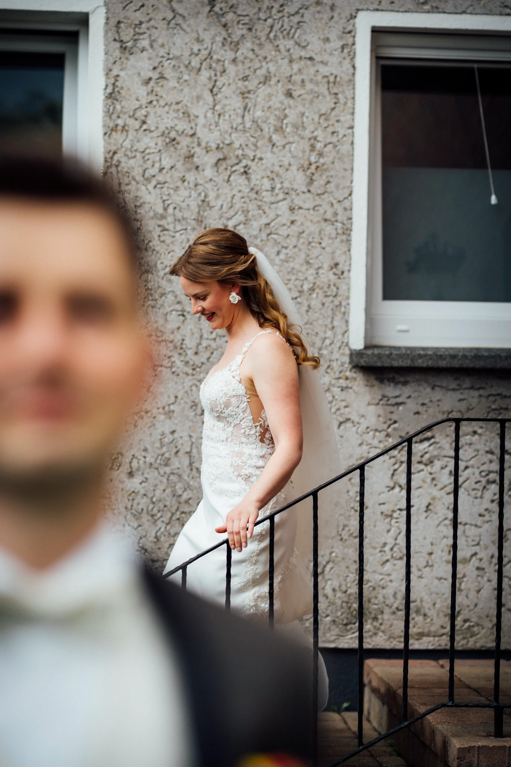 Die Braut kommt für den First Look die Treppe hinunter in den Garten