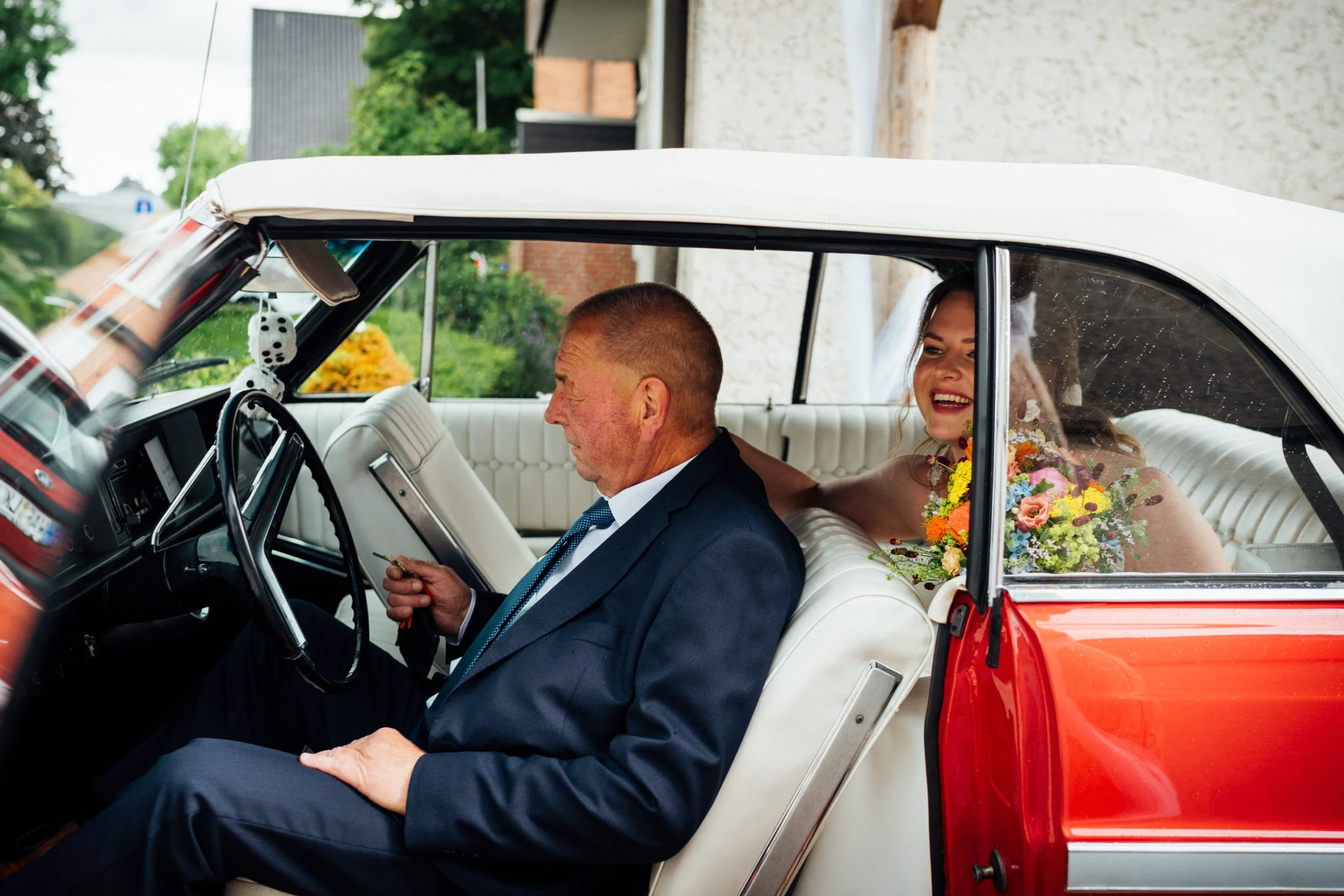 Die Braut sitzt mit ihrem Vater im Oldtimer auf dem Weg zur freien Trauung