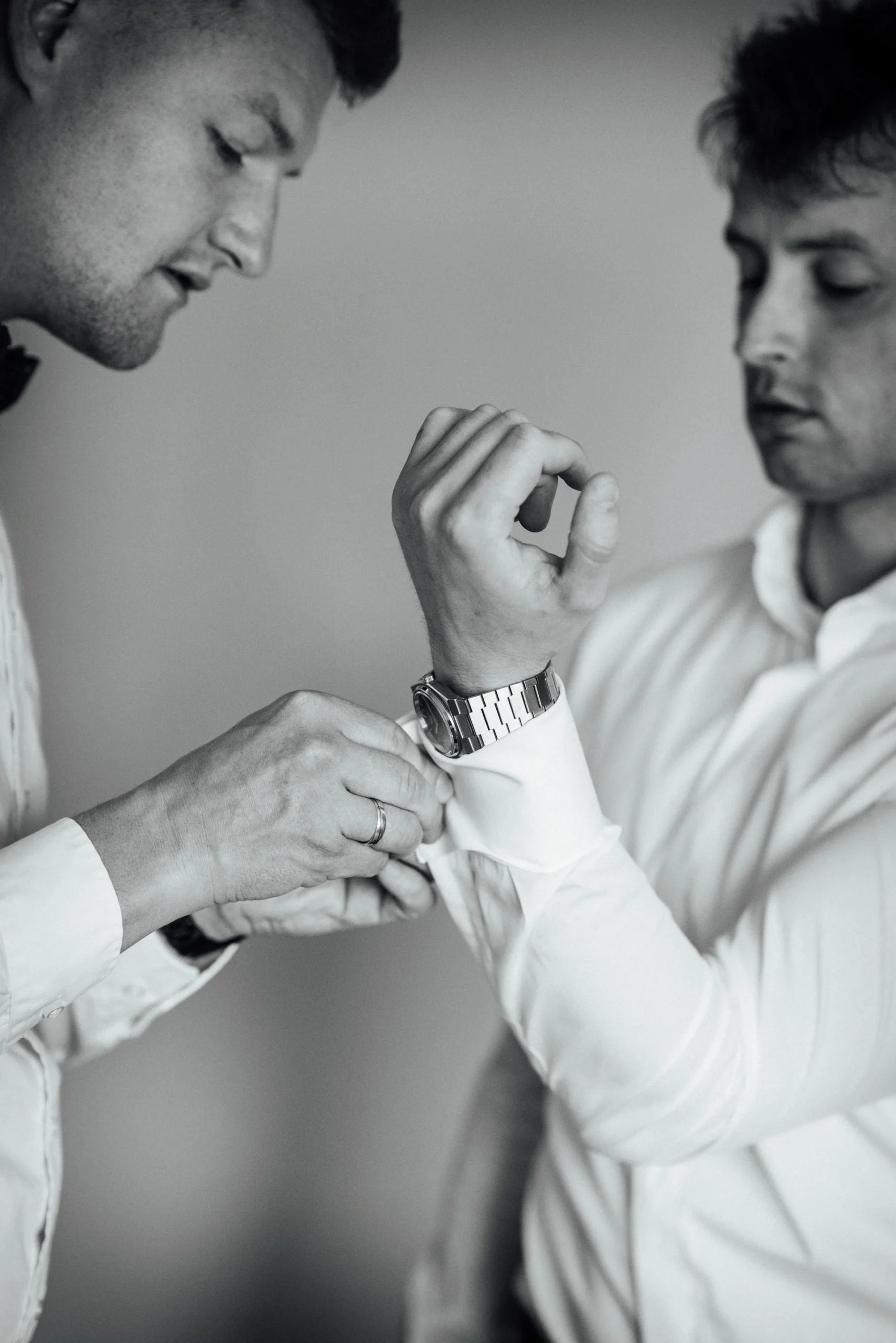 Ein Trauzeuge hilft dem Bräutigam beim Anlegen der Manschettenknöpfe