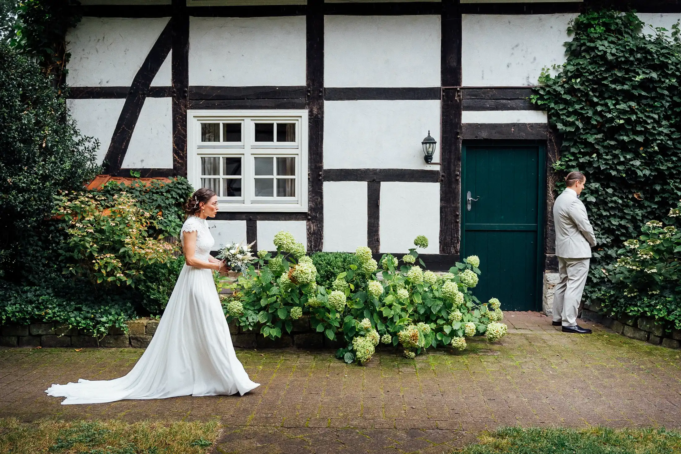Die Braut geht beim First Look im gastlichen Dorf heimlich auf den wartenden Bräutigam zu