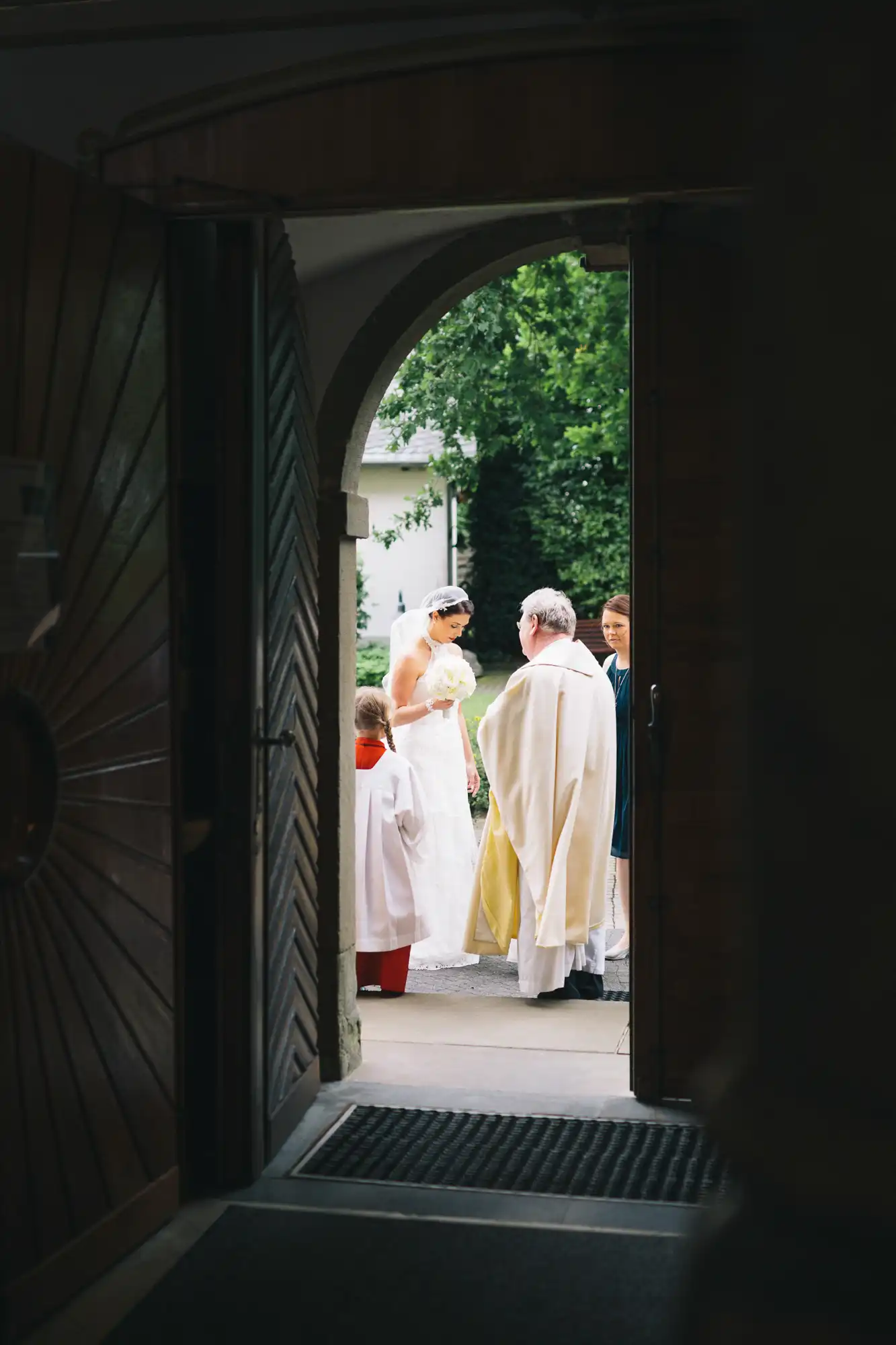 Pfarrer empfängt die Braut und ihren Vater vor der Kirche