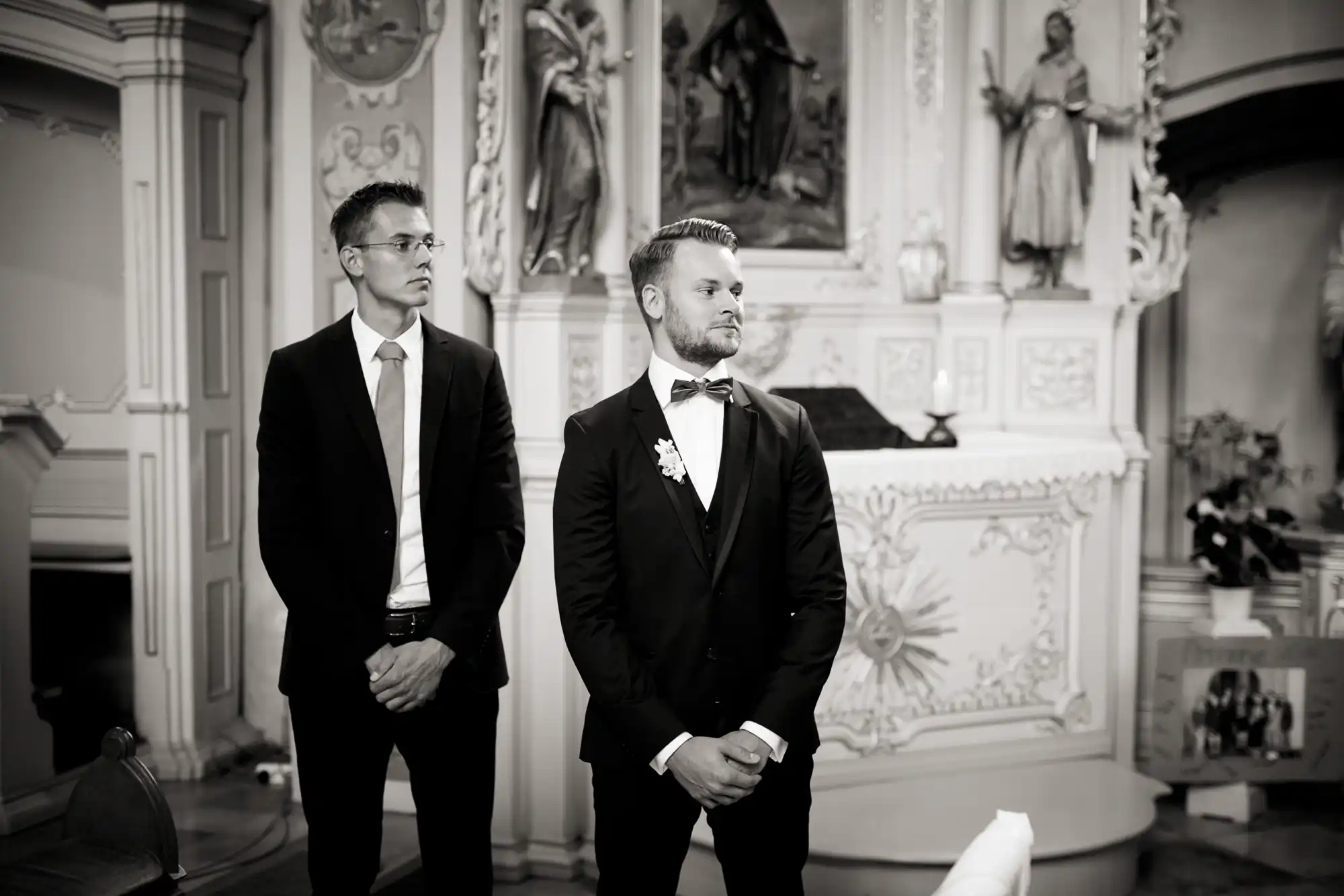 Bräutigam und Trauzeuge blicken zur Braut während sie in die Kirche einzieht